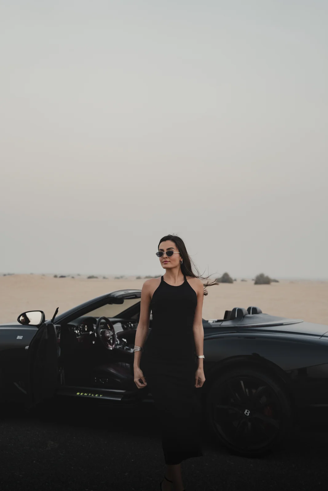 Wider portrait frame showing model, side of car and desert.