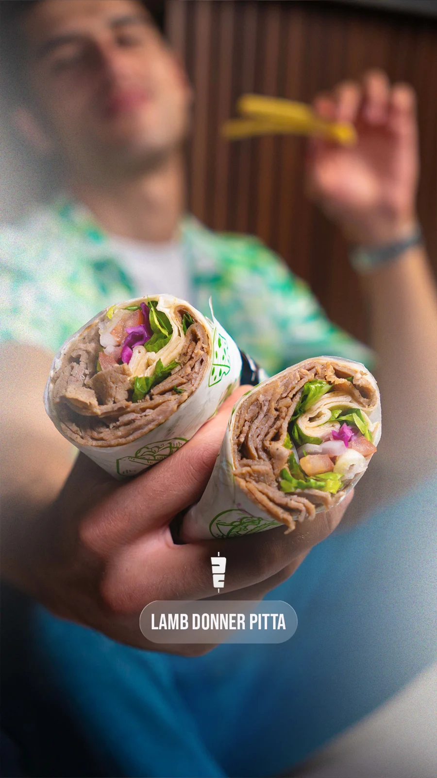 Pitta halves held toward camera, diner softly blurred behind.