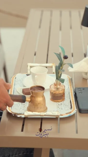 Server carries a decorative coffee tray and pours at the table.